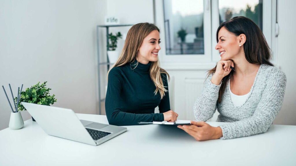 Two smiling female colleagues in the office. Working together.